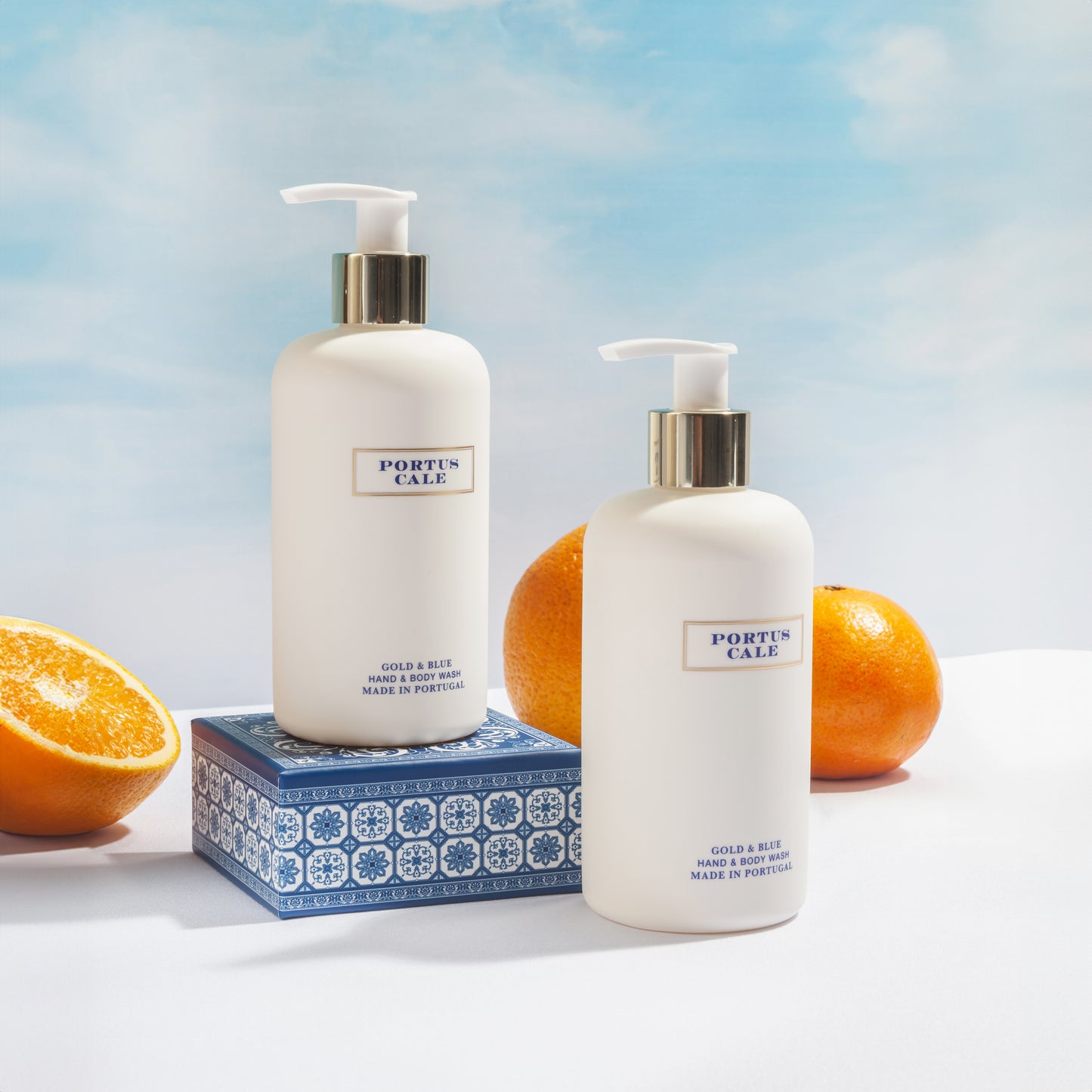 Portus Cale Gold Blue hand and body wash on white shelf with oranges in the background