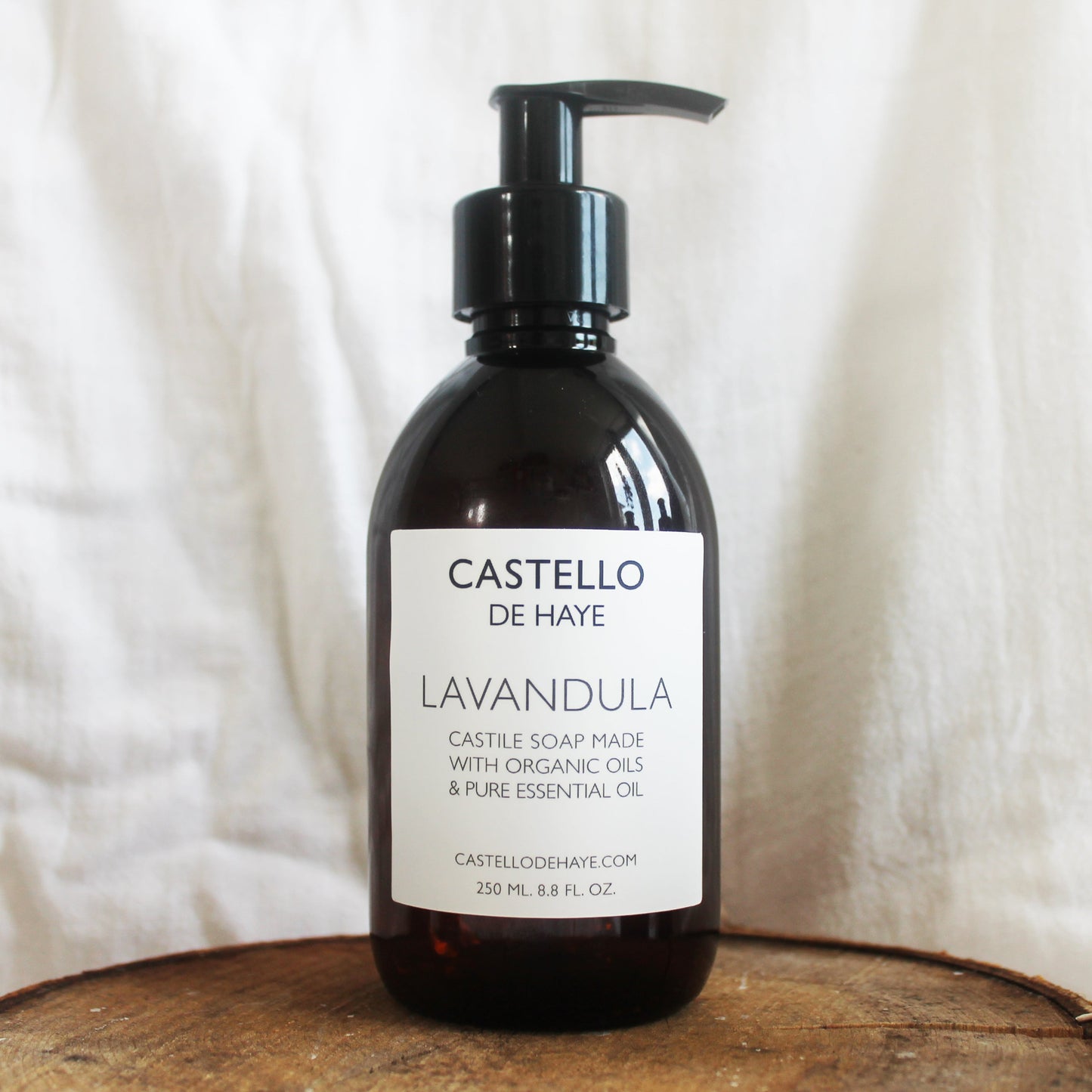 Lavandula castile soap in amber bottle with pump on wooden tray with linen backdrop