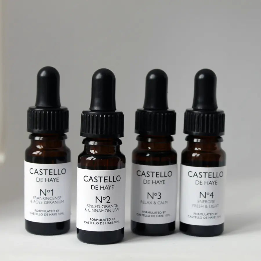 Four Castello de Haye essential oil dropper bottles on a gray background