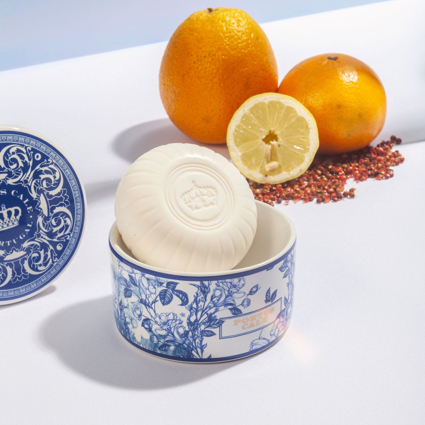 White bar of soap in a blue and white decorative bowl with oranges and a lemon on a light blue background