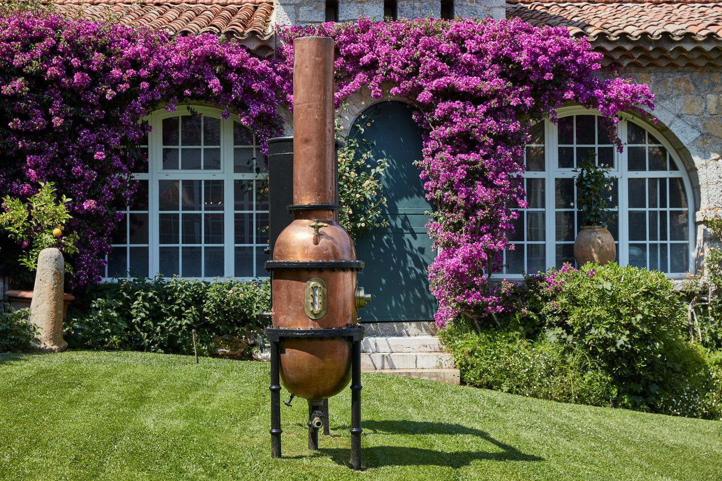 Durance Grasse copper oil distiller on grass with flowers in the background