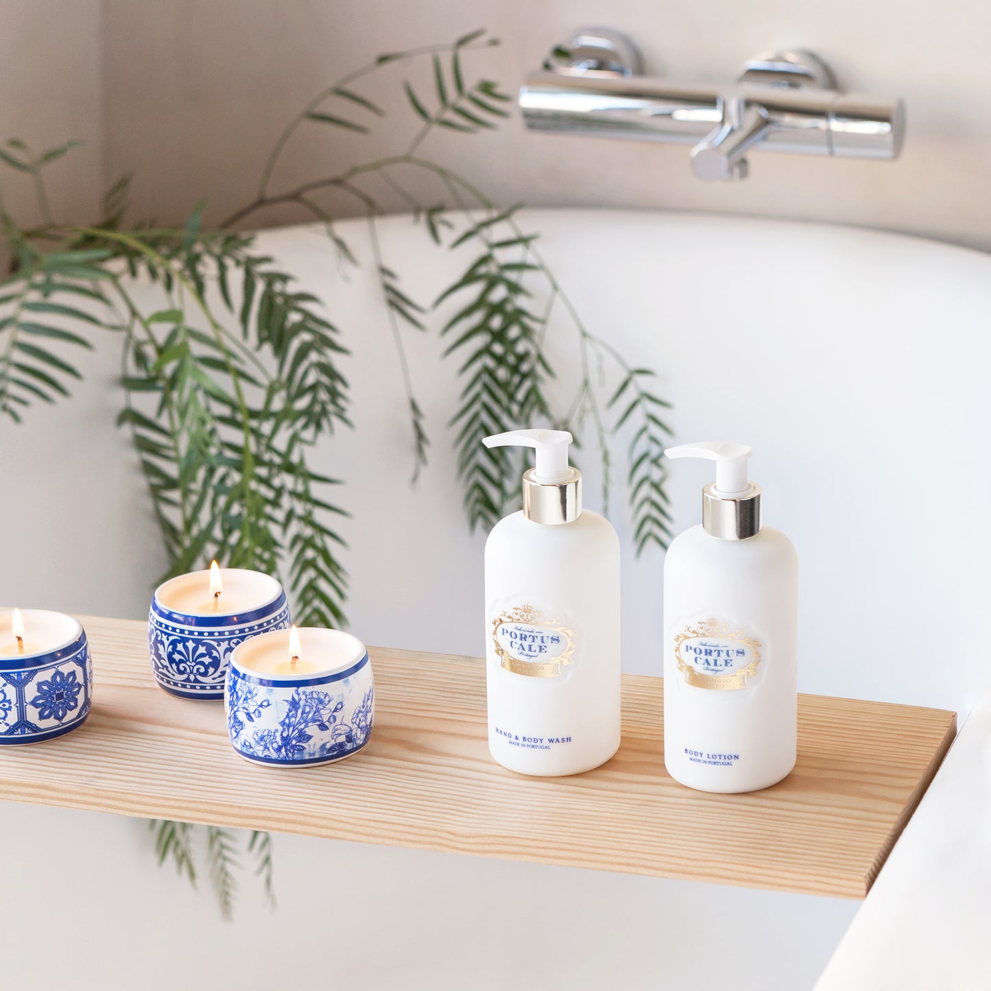 Portus Cale Gold Blue hand and body wash with candles on a bath tray over a white bath tub