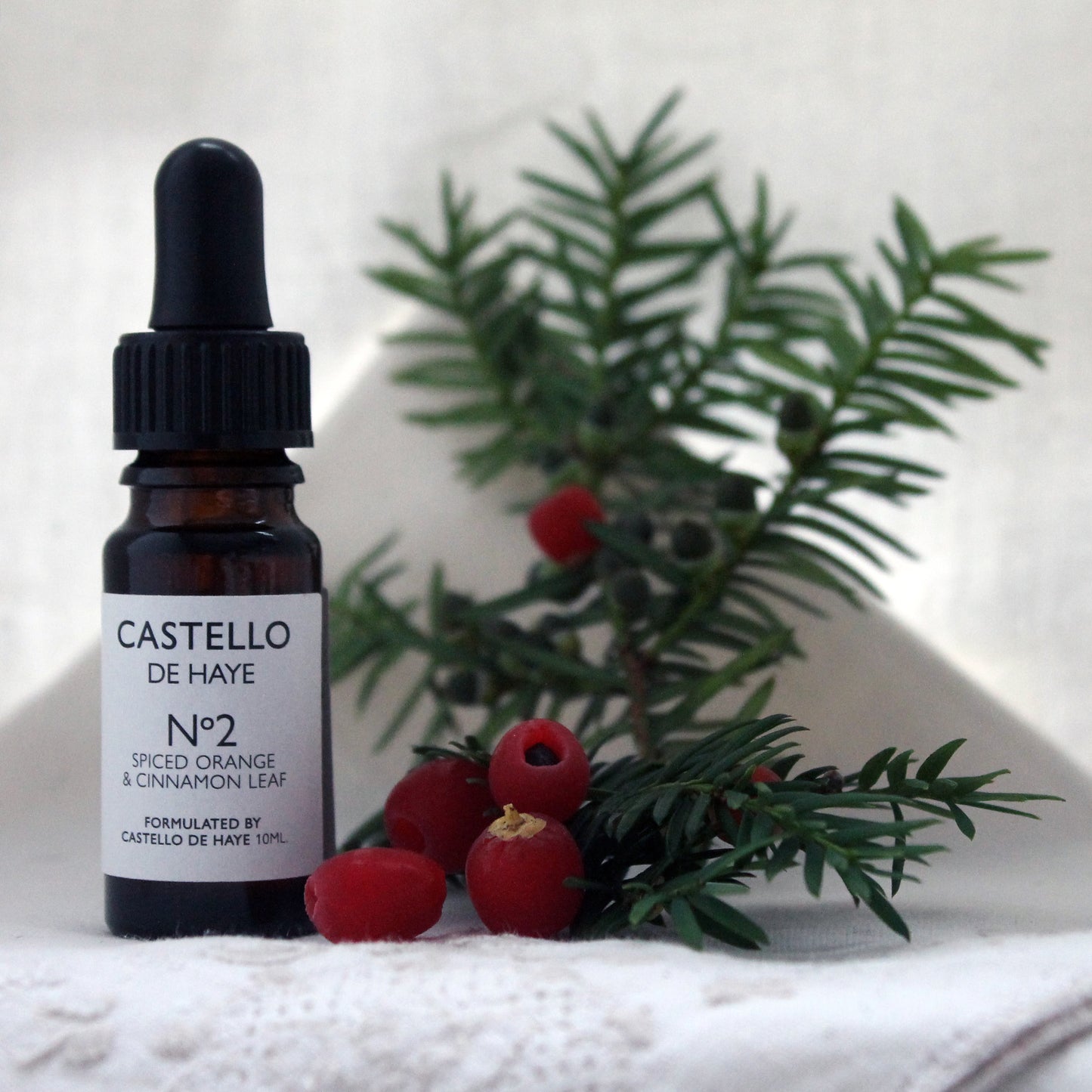 10ml amber bottle of spiced orange and cinnamon leaf essential oil in a dropper bottle with yew leaves and berries