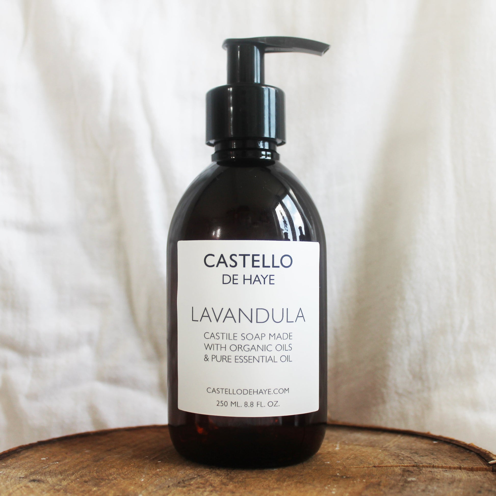 Lavandula castile soap in amber bottle with pump on wooden tray with linen backdrop